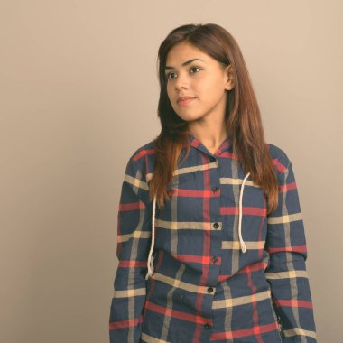 Stüdyo çekim giyen genç güzel Hintli kadın gömlek gri arka plan kontrol