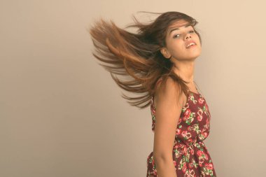 Genç güzel Hint kadının elbise saç gri arka plan karşı saygısız Studio vurdu