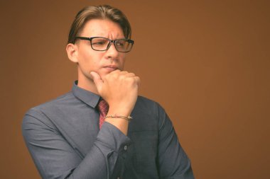 Mavi gömlek ve gözlük kahverengi zemin karşı giyen işadamı stüdyo çekim