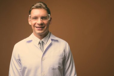 Kahverengi zemin karşı koruyucu gözlük takan adam doktor stüdyo çekim