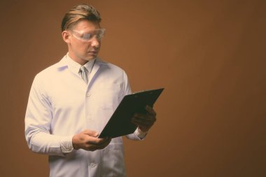 Kahverengi zemin karşı koruyucu gözlük takan adam doktor stüdyo çekim