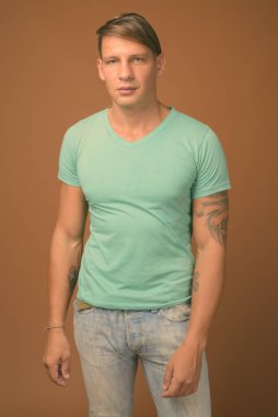 Kahverengi zemin karşı yeşil gömlek giyen kaslı adam stüdyo çekim