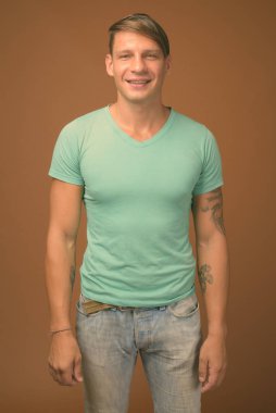 Kahverengi zemin karşı yeşil gömlek giyen kaslı adam stüdyo çekim