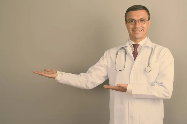 灰色の背景の眼鏡を身に着けている男性医師のスタジオ撮影 — ストック写真
