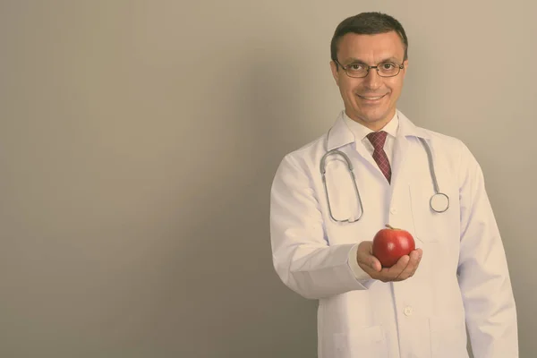 摄影棚拍摄的男子医生戴眼镜 而持有红苹果对灰色背景 — 图库照片