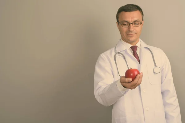 Strzał Studio Lekarza Man Noszenia Okularów Trzymając Czerwone Jabłko Szarym — Zdjęcie stockowe