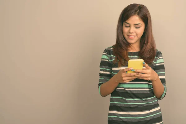 Студия Фотографии Молодой Красивой Индийской Женщины Использующей Мобильный Телефон Сером — стоковое фото
