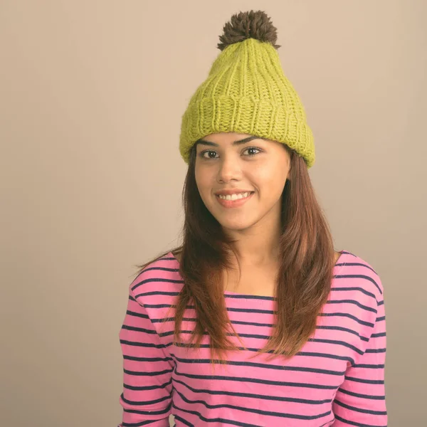 Gri bir arka plana dayanır örme şapka giyen genç güzel Hint kadın stüdyo çekim