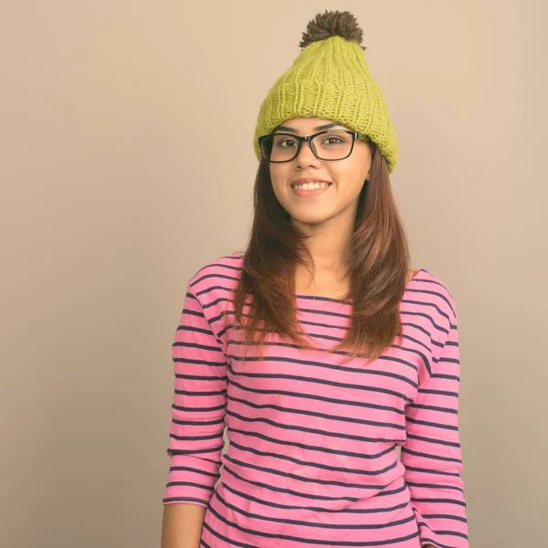 Gri bir arka plana dayanır örme şapka giyen genç güzel Hint kadın stüdyo çekim