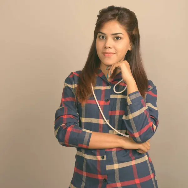 Stüdyo çekim giyen genç güzel Hintli kadın gömlek gri arka plan kontrol