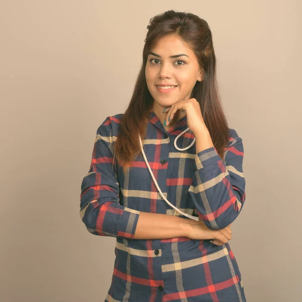 Stüdyo çekim giyen genç güzel Hintli kadın gömlek gri arka plan kontrol