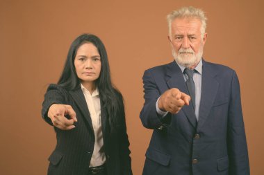 Üst düzey iş adamı ve kahverengi zemin karşı birlikte Olgun Asya işkadını stüdyo çekim