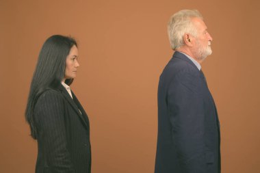 Üst düzey iş adamı ve kahverengi zemin karşı birlikte Olgun Asya işkadını stüdyo çekim