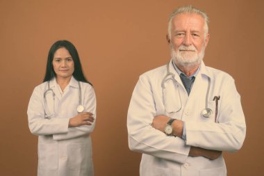 Komuta sizde doktor ve olgun Asyalı kadın doktor kahverengi zemin karşı birlikte stüdyo çekim