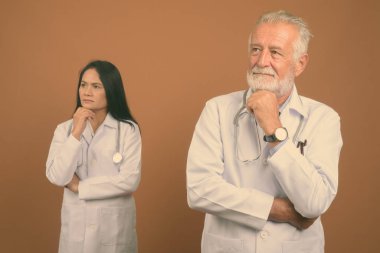 Komuta sizde doktor ve olgun Asyalı kadın doktor kahverengi zemin karşı birlikte stüdyo çekim