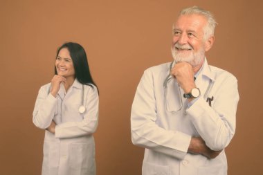 Komuta sizde doktor ve olgun Asyalı kadın doktor kahverengi zemin karşı birlikte stüdyo çekim