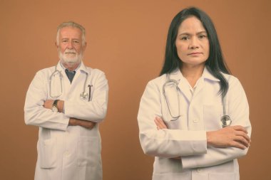 Komuta sizde doktor ve olgun Asyalı kadın doktor kahverengi zemin karşı birlikte stüdyo çekim