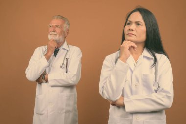Komuta sizde doktor ve olgun Asyalı kadın doktor kahverengi zemin karşı birlikte stüdyo çekim