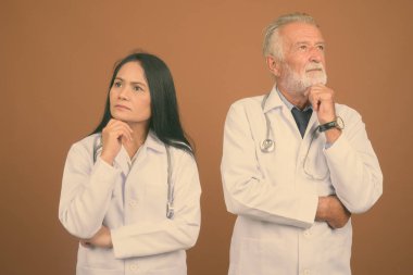 Komuta sizde doktor ve olgun Asyalı kadın doktor kahverengi zemin karşı birlikte stüdyo çekim