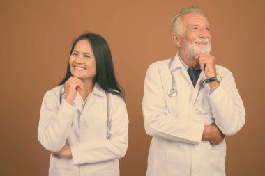 Komuta sizde doktor ve olgun Asyalı kadın doktor kahverengi zemin karşı birlikte stüdyo çekim