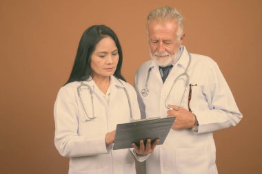 Komuta sizde doktor ve olgun Asyalı kadın doktor kahverengi zemin karşı birlikte stüdyo çekim