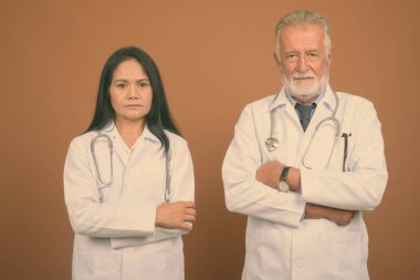 Komuta sizde doktor ve olgun Asyalı kadın doktor kahverengi zemin karşı birlikte stüdyo çekim