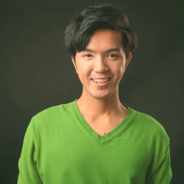 Young handsome Asian man against black background