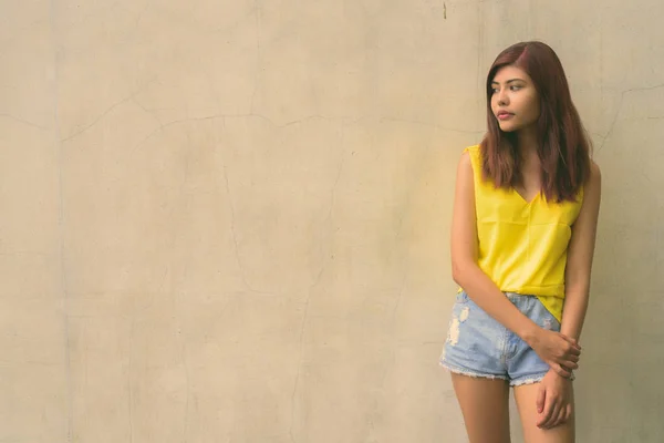 屋外灰色の背景に鮮やかな黄色のシャツを着て美しいティーンエイ ジャーの女の子 — ストック写真