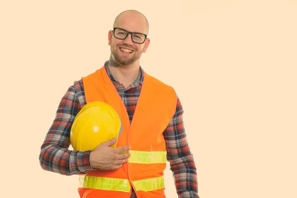 Feliz calvo musculoso trabajador de la construcción sonriendo mientras sostiene el casco de seguridad —  Fotos de Stock