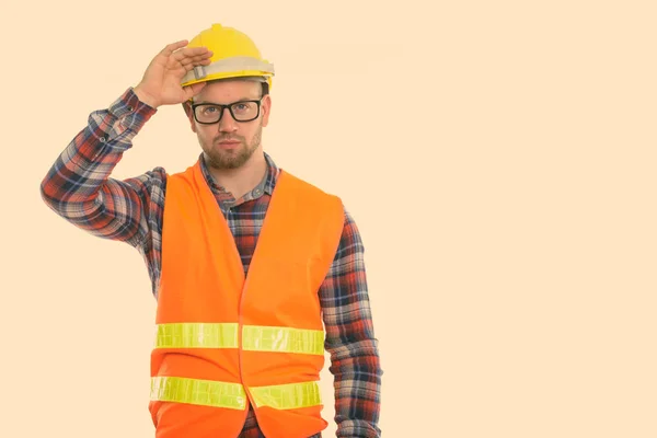 Молодий лисий м'язистий чоловік будівельник тримає шолом безпеки на голові — стокове фото