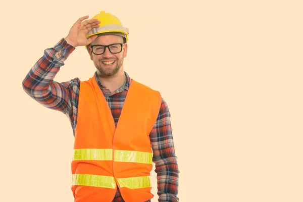 Щасливий лисий м'язистий чоловік будівельник посміхається, тримаючи шолом безпеки на голові — стокове фото