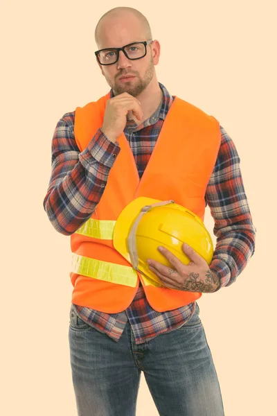 Лисий м'язистий чоловік будівельник думає, тримаючи шолом безпеки — стокове фото
