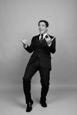 Studio shot of handsome Persian businessman against gray background in black and white