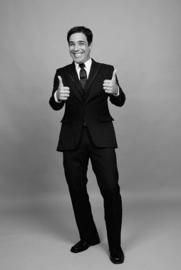 Studio shot of handsome Persian businessman against gray background in black and white