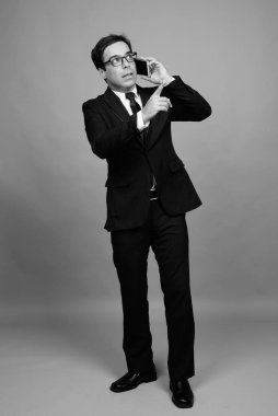 Studio shot of handsome Persian businessman against gray background in black and white