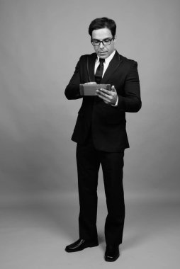 Studio shot of handsome Persian businessman against gray background in black and white