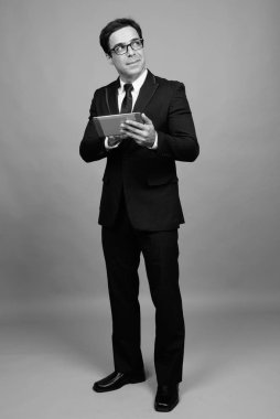 Studio shot of handsome Persian businessman against gray background in black and white