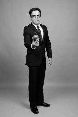 Studio shot of handsome Persian businessman against gray background in black and white