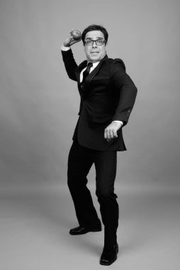 Studio shot of handsome Persian businessman against gray background in black and white