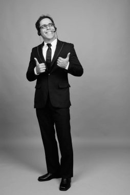Studio shot of handsome Persian businessman against gray background in black and white