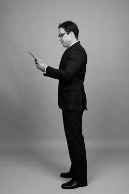 Studio shot of handsome Persian businessman against gray background in black and white