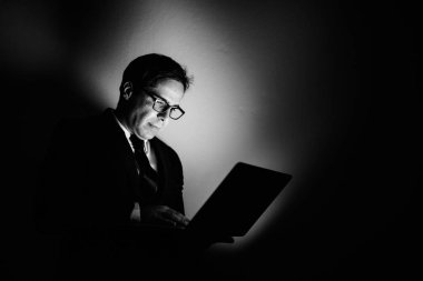 Studio shot of handsome Persian businessman against gray background in black and white