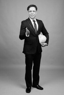 Studio shot of handsome Persian businessman against gray background in black and white