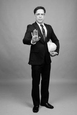 Studio shot of handsome Persian businessman against gray background in black and white
