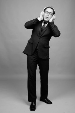 Studio shot of handsome Persian businessman against gray background in black and white