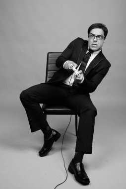 Studio shot of handsome Persian businessman against gray background in black and white