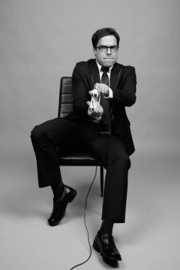 Studio shot of handsome Persian businessman against gray background in black and white