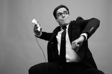 Studio shot of handsome Persian businessman against gray background in black and white