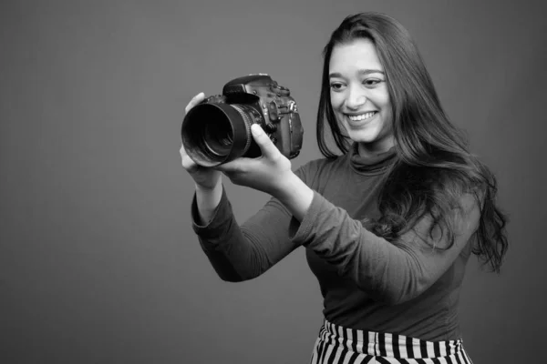 Mladá krásná indická žena s kamerou proti šedému pozadí — Stock fotografie