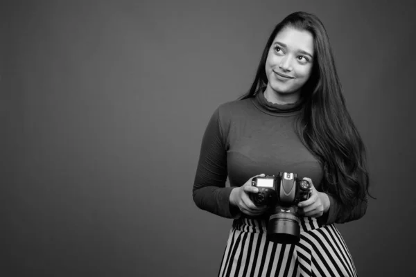 Jong mooi indisch vrouw met camera tegen grijs achtergrond — Stockfoto